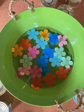 Bunte Papierblüten schwimmen in einer grünen Schüssel.